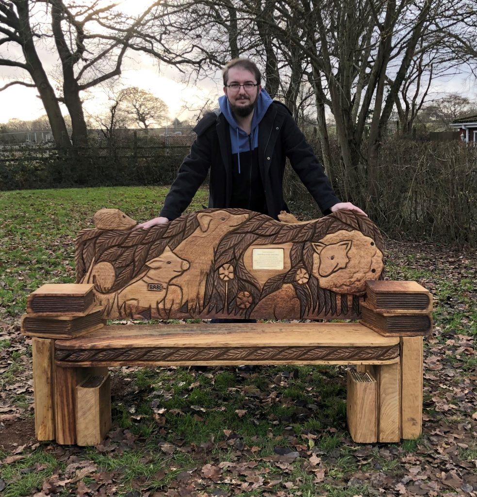 Tristan Clark with the new bench which is made of wood with animals carved into it. 