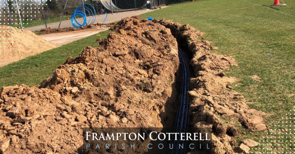 Photograph of a deep, narrow trench in The Park cricket pitch. The Frampton Cotterell Parish Council Logo is on the lower middle of the photo.