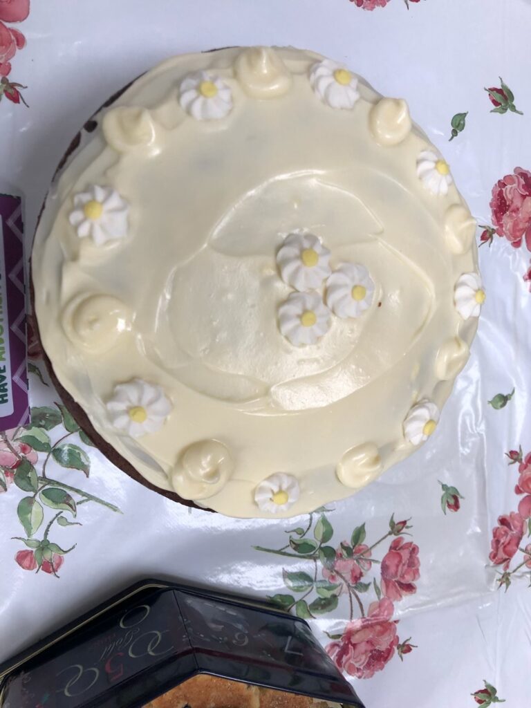 Top down view of a pearlescent white cake, decorated with white and yellow daisies.