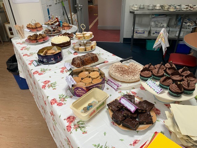 A long table with many cakes, cupcakes, brownies, flapjacks etc. on it.